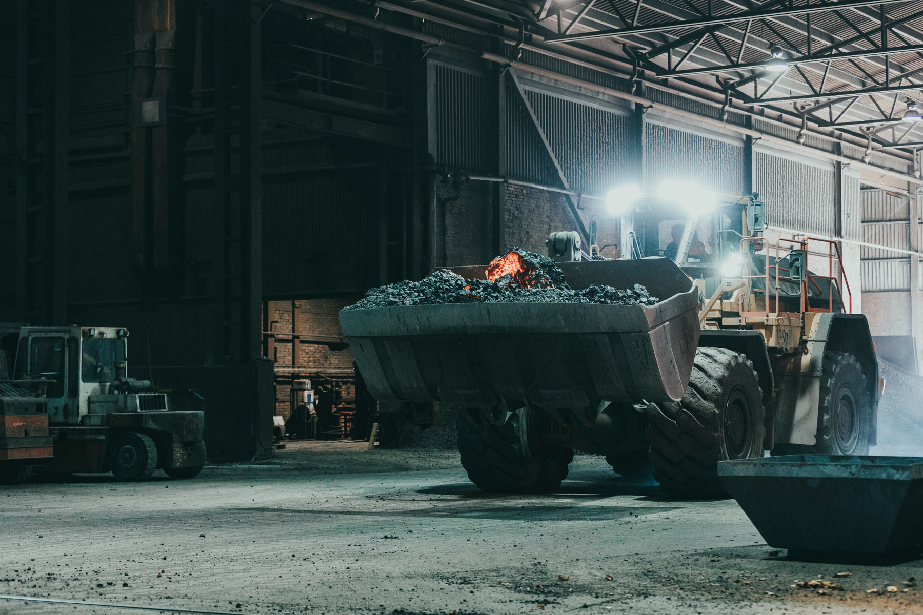 Foto på en grävskopa som kör glödande kol på Vargön Alloys